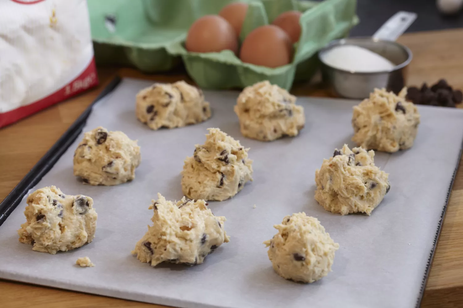 Freshly made chocolate chip and peanut cookie dough with ingredients on kitchen worktop ready for baking