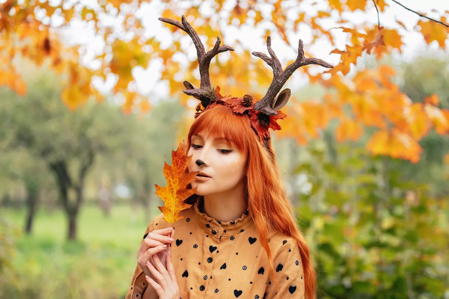 fairy woman with deer horns in autumn forest. Face painting. Beautiful mystery woman. redhead girl with big eyes magical sight